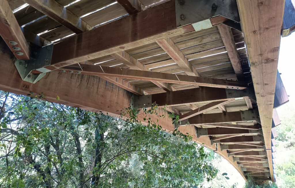 En la imagen, la cara inferior de un puente de madera permite observar la lógica constructiva...